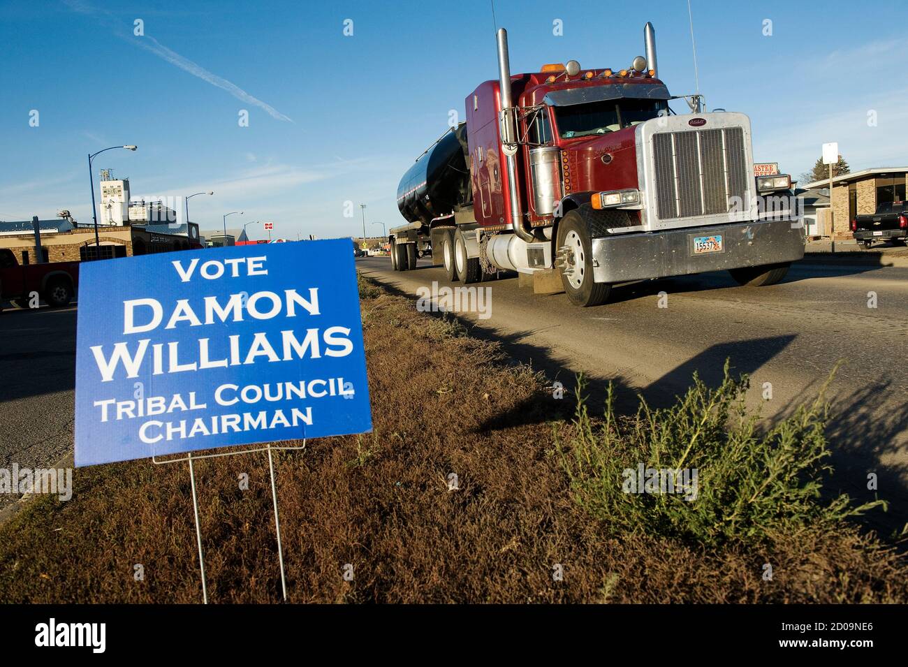 Oil field traffic passes a campaign sign for Three Affiliated Tribes council chairman candidate Damon Williams in New Town on the Fort Berthold Reservation in North Dakota, November 1, 2014. The Fort Berthold Indian Reservation, home to the Mandan, Hidatsa, and Arikara Nation, produces nearly a third of North Dakota's oil. The election for a new tribal chairman, in which both candidates have positioned themselves as reformers, may change the oil industry's relationship with the reservation. Photo taken November 1, 2014.   REUTERS/Andrew Cullen   (UNITED STATES - Tags: POLITICS ELECTIONS) Stock Photo