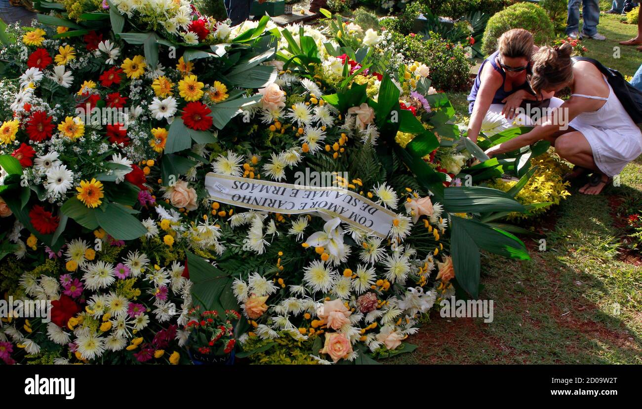 Women place flowers on the grave of Brazil's 1982 World Cup captain Socrates during his funeral ceremony in Ribeirao Preto December 4, 2011. Socrates, the 'Golden Heel' renowned as one of the great playmakers of his generation, died in hospital on Sunday of septic shock at the age of 57, his doctors said in a statement. REUTERS/Paulo Whitaker (BRAZIL - Tags: SPORT SOCCER OBITUARY) Stock Photo