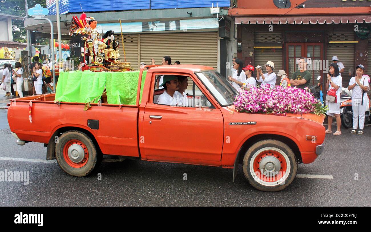Phuket Vegetarian Festival or Nine Emperor Gods Festival street procession, parade with a Chinese Taoist Statue in back of old, orange Datsun pickup Stock Photo
