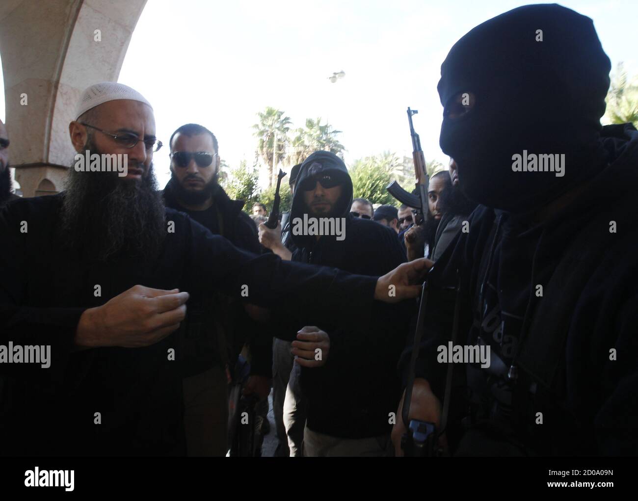 Lebanon's Sunni Muslim Salafist leader Ahmad al-Assir (L) asks a supporter  to remove his mask during the funeral of two of his supporters, who died  during Sunday's fighting with supporters of Lebanon's