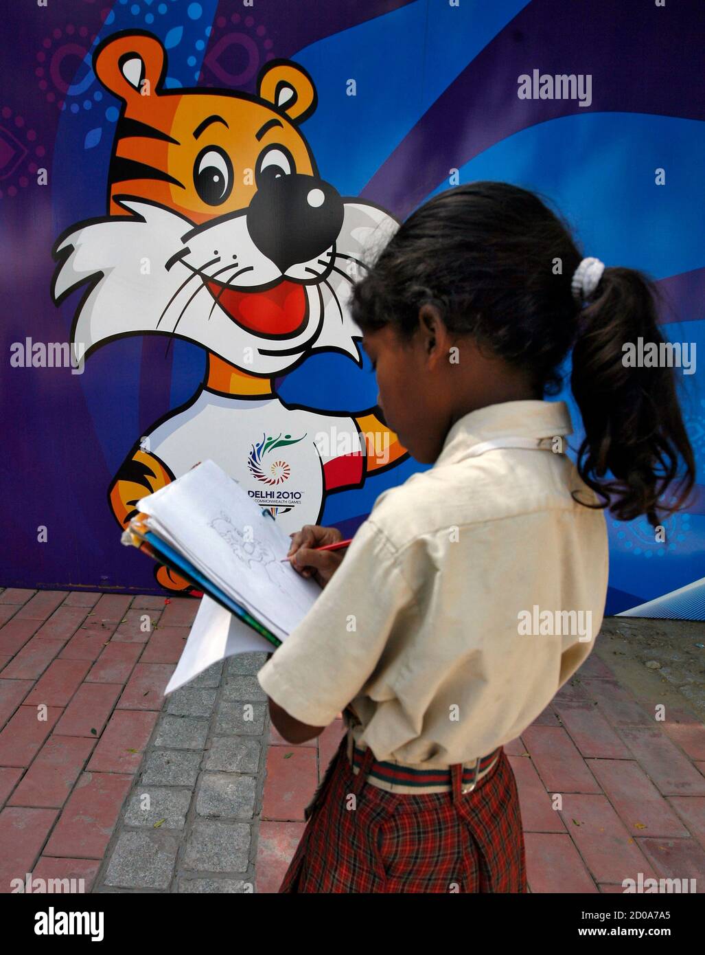 A schoolgirl makes a drawing of the mascot of the Commonwealth Games on a  roadside outside the Jawaharlal Nehru Stadium in New Delhi September 29,  2010. Athletes got down to training on