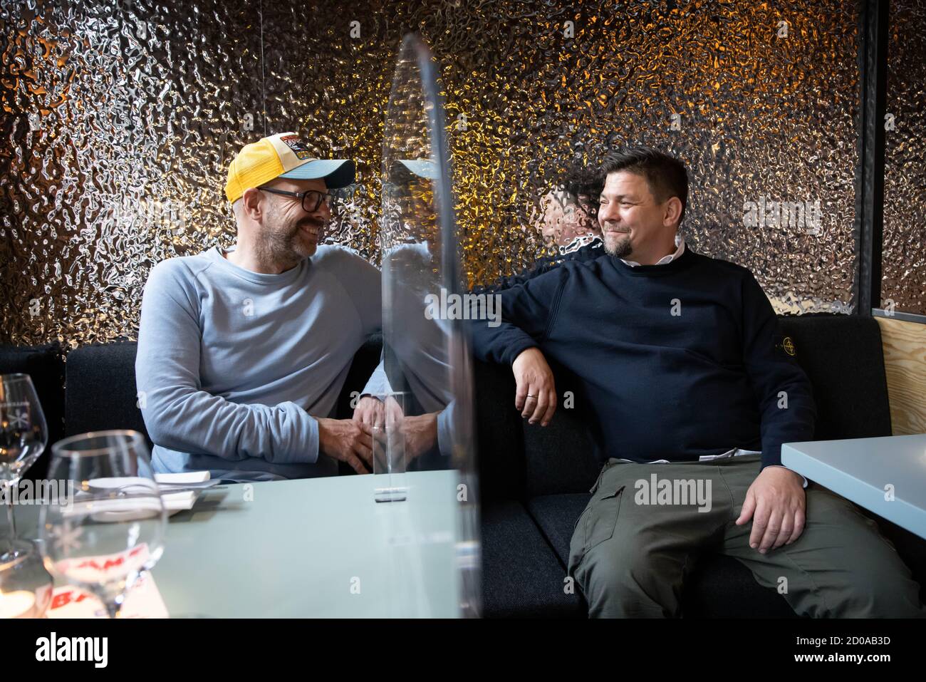 Hamburg, Germany. 02nd Oct, 2020. TV chef Tim Mälzer (r) and Patrick Rüther, restaurateur and business partner, sit at a table in the newly designed rooms of their restaurant 'Bullerei'. A Corona-conditioned separating plate made of Plexiglas is mounted on the table. (to 'Tim Mälzer's 'Bullerei' opens again after a six-month compulsory break') Credit: Christian Charisius/dpa/Alamy Live News Stock Photo