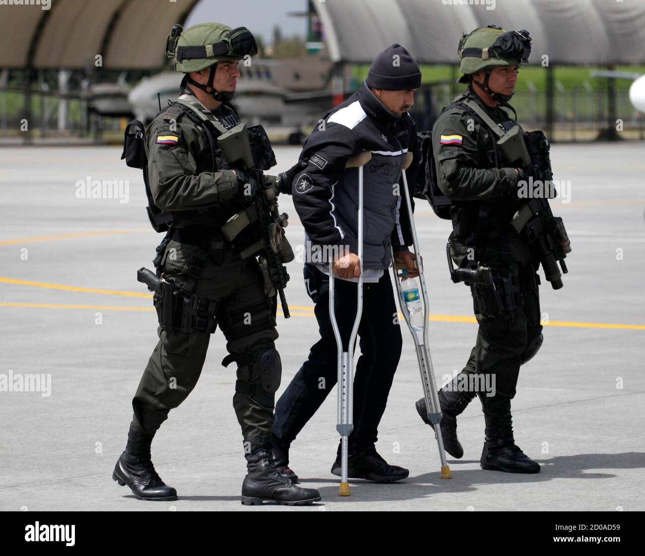 Colombian Edison Castro Lopez (C), also known as 'Jairo' or 'Chicanero,' is escorted by the Colombian National Police after being deported from Ecuador at a military base, in Bogota August 6, 2012. Lopez, who is a suspected member of the Revolutionary Armed Forces of Colombia (FARC), was captured during a joint operation between the Colombian and Ecuadorian police in Ecuador for drug and weapon trafficking, according to local media.  REUTERS/John Vizcaino (COLOMBIA - Tags: CRIME LAW POLITICS MILITARY DRUGS SOCIETY) Stock Photo