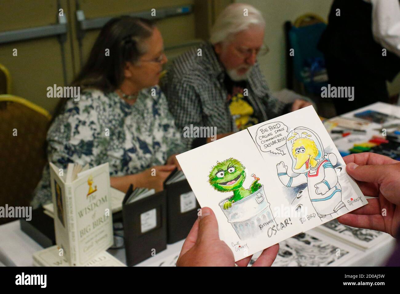A man displays sketches by Caroll Spinney (back R) as he signs autographs during the Dean Martin Expo and Nostalgic, Comedy and Comic Convention featuring collection of memorabilia from the 1950's and 60's, in New York June 28, 2014. REUTERS/Eduardo Munoz (UNITED STATES - Tags: ENTERTAINMENT SOCIETY) Stock Photo