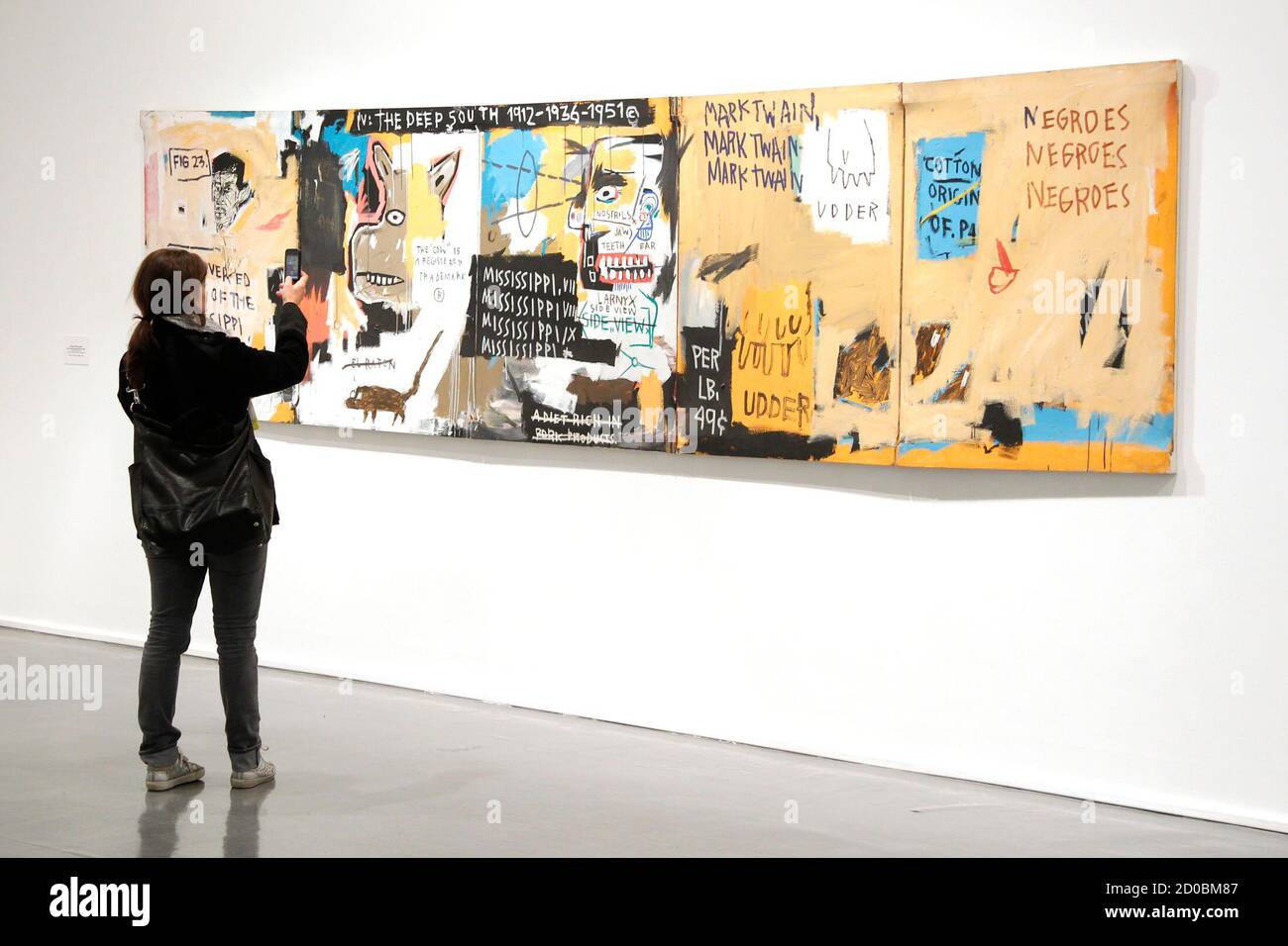 A visitor takes a picture of the painting "Undiscovered Genius of  Mississippi Delta, 1983" by U.S. artist Jean-Michel Basquiat (1960-1988)  before the opening of the exhibition "Basquiat" at the Museum of Modern