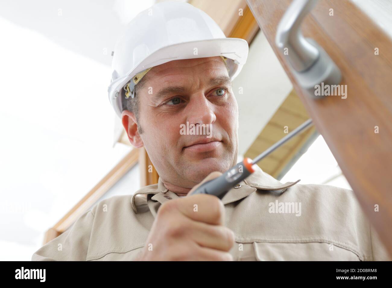 service man installing window with screwdriver Stock Photo
