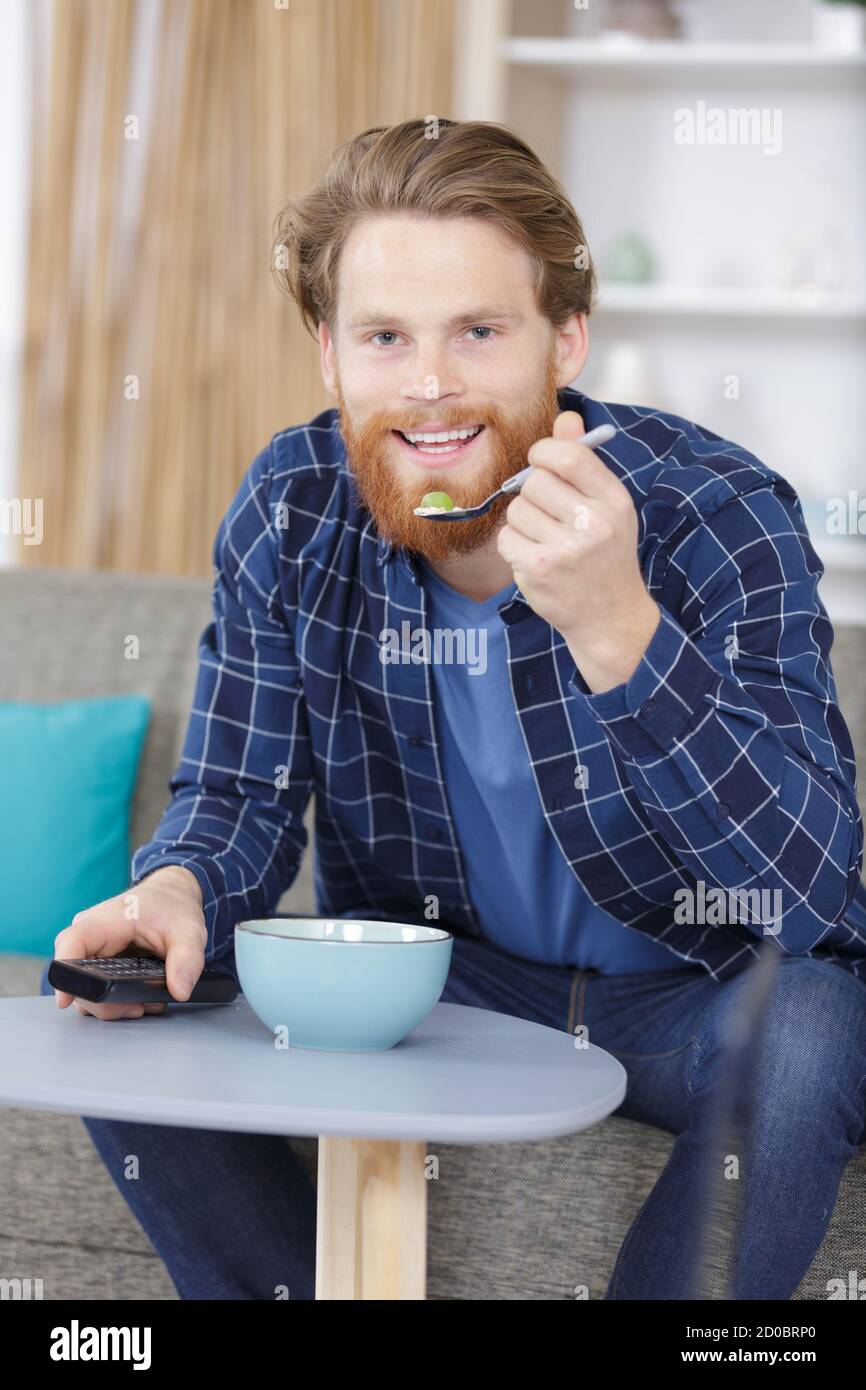 man with a bowl of cereals watching tv Stock Photo