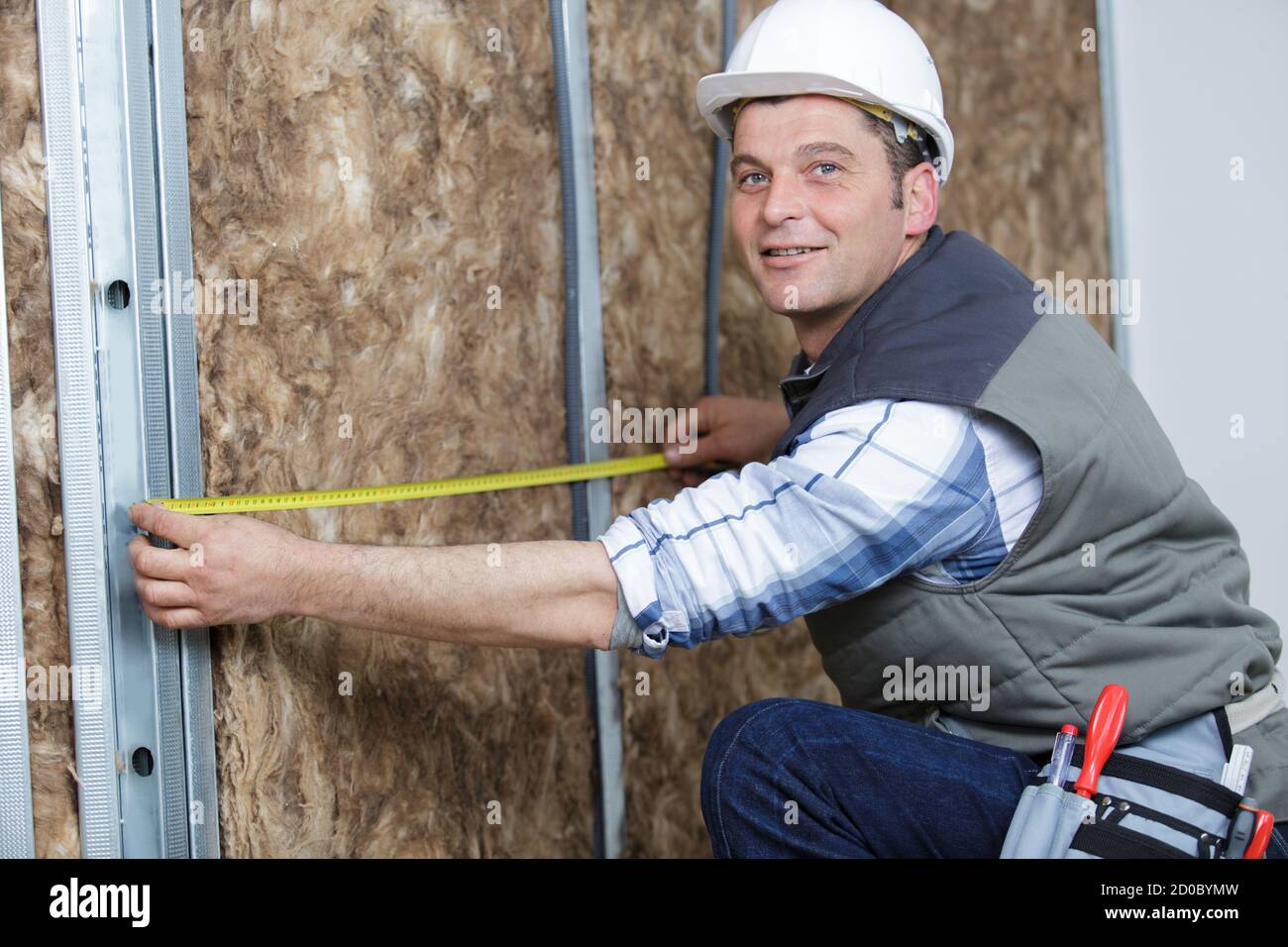 young man measures a warmed wall Stock Photo