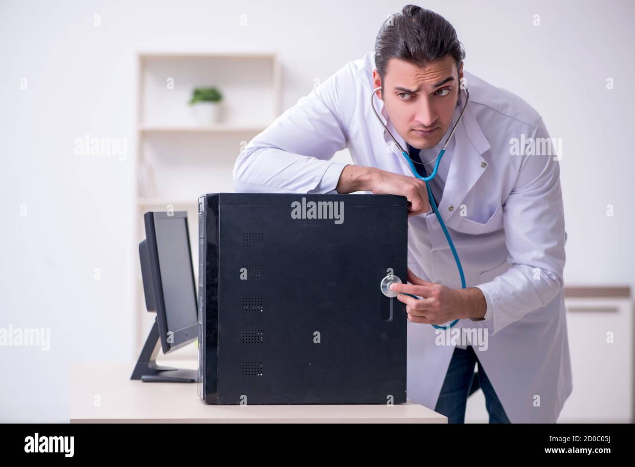 Young doctor with stethoscope repairing computer Stock Photo - Alamy