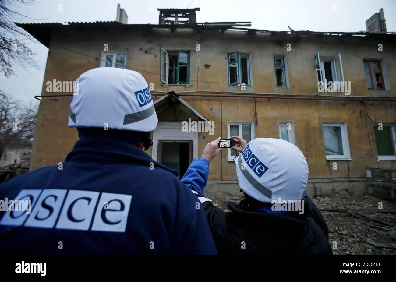 An Organization for Security and Cooperation in Europe (OSCE) investigator takes pictures of a building after it was damaged by recent shelling in the western part of Donetsk, eastern Ukraine, November 27, 2014. REUTERS/Antonio Bronic (UKRAINE  - Tags: CONFLICT CIVIL UNREST) Stock Photo