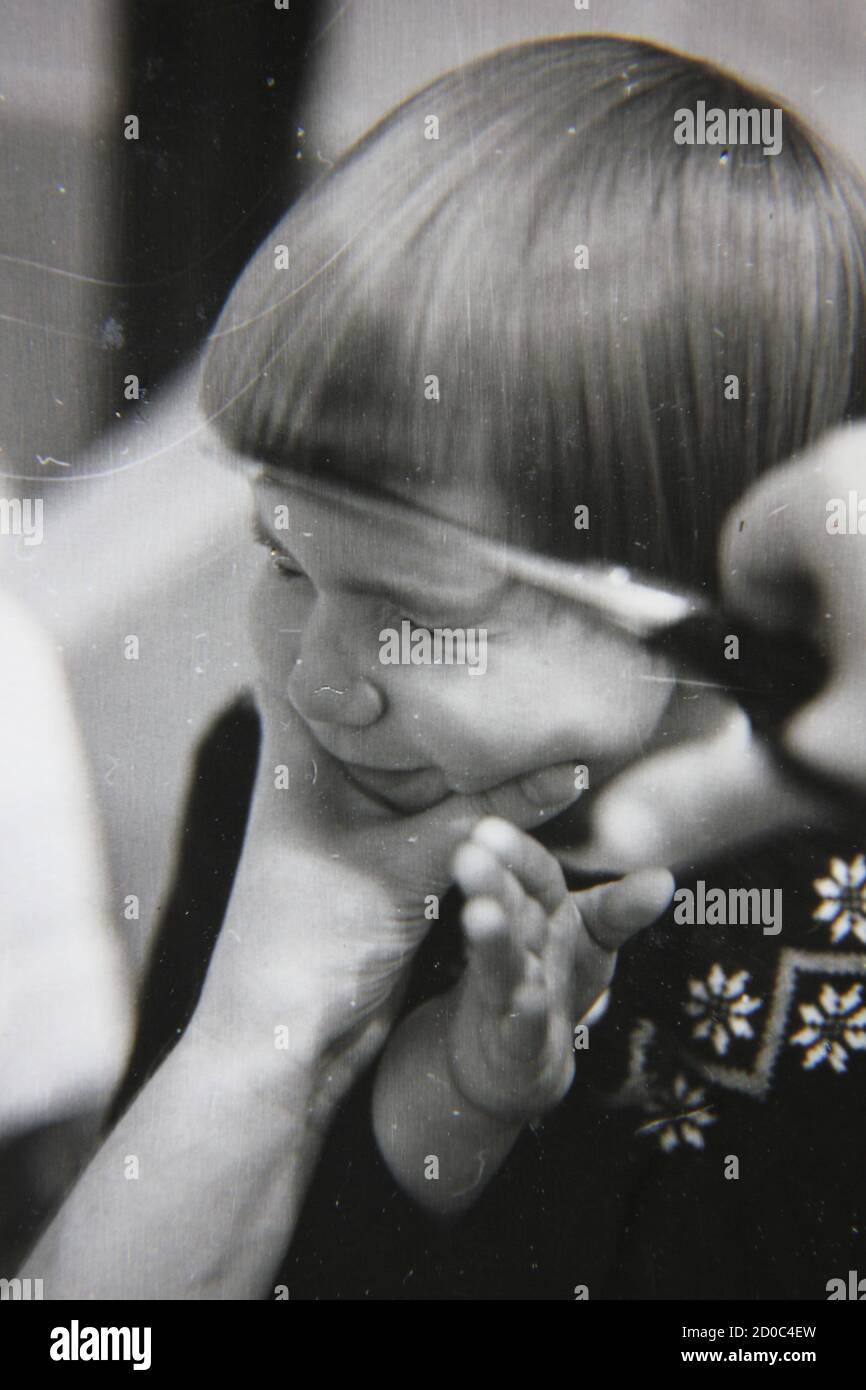Fine 1970s vintage black and white photography of a little girl getting her hair cut in a page boy homemade style. Stock Photo