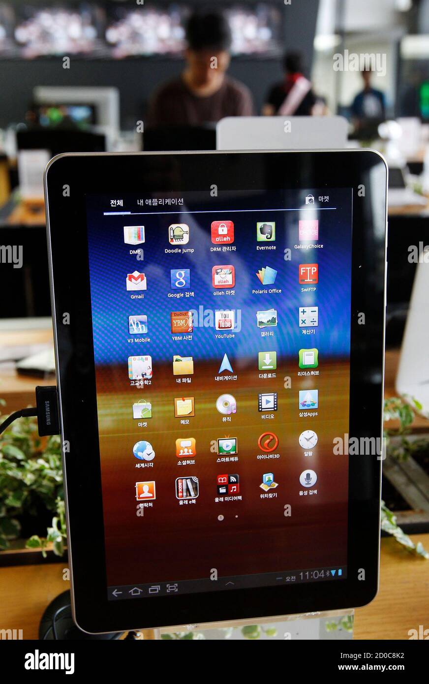 A customer looks at smartphones behind a Samsung Electronics' Galaxy Tab  10.1 on display at a registration desk at South Korean mobile carrier KT's  headquarters in Seoul, August 10, 2011. Apple Inc