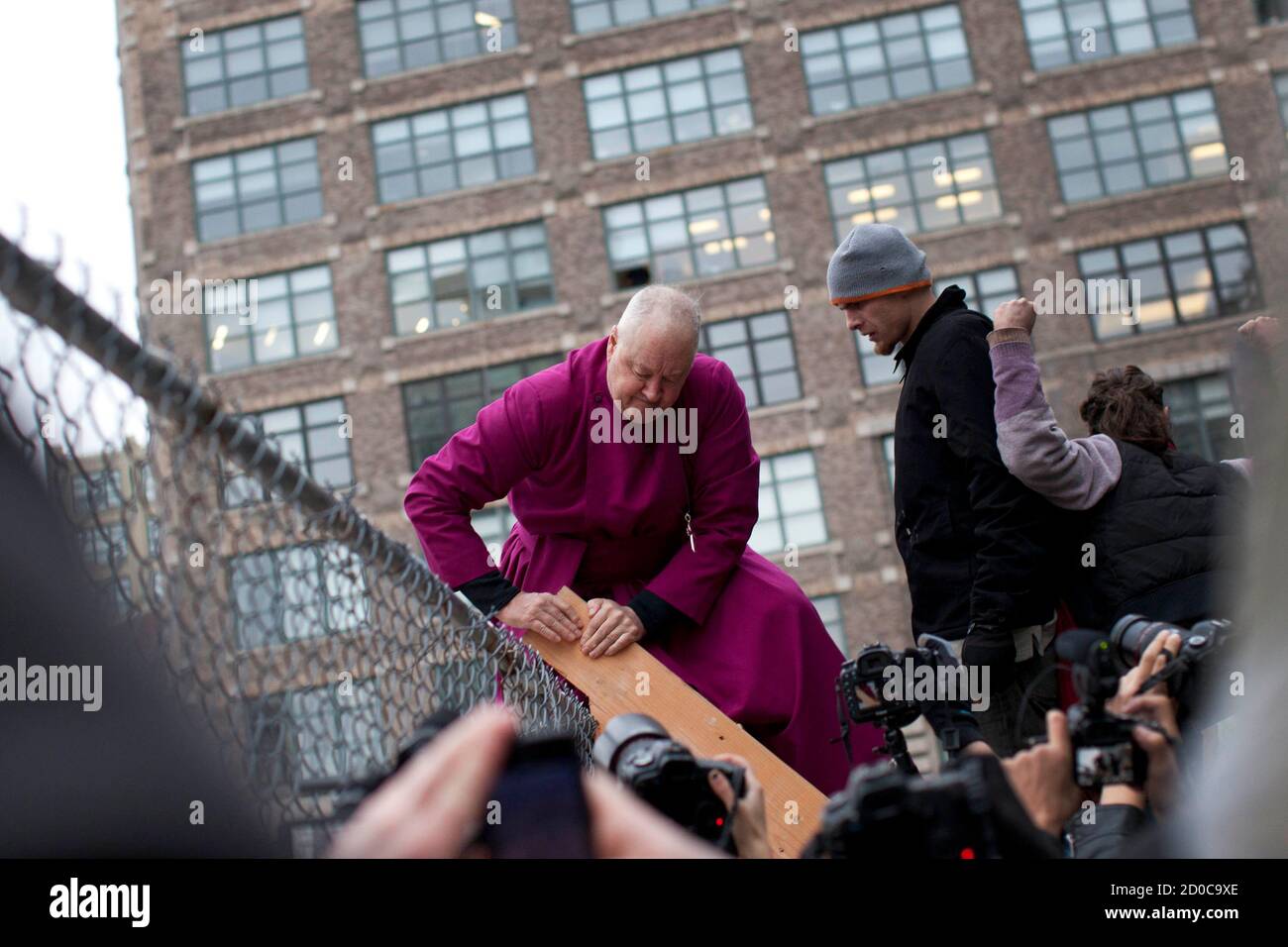 Retired Episcopal bishop George E. Packard (L), who is affiliated with the Occupy Wall Street movement, climbs a ladder to illegally trespass on a privately-owned piece of land near Juan Pablo Duarte Square during a march in New York December 17, 2011. Hundreds of anti-Wall Street protesters took to the New York streets on Saturday in an attempt to establish a new encampment, with a number arrested as they tried to move onto church-owned land. REUTERS/Andrew Burton (UNITED STATES - Tags: CIVIL UNREST POLITICS BUSINESS RELIGION TPX IMAGES OF THE DAY) Stock Photo