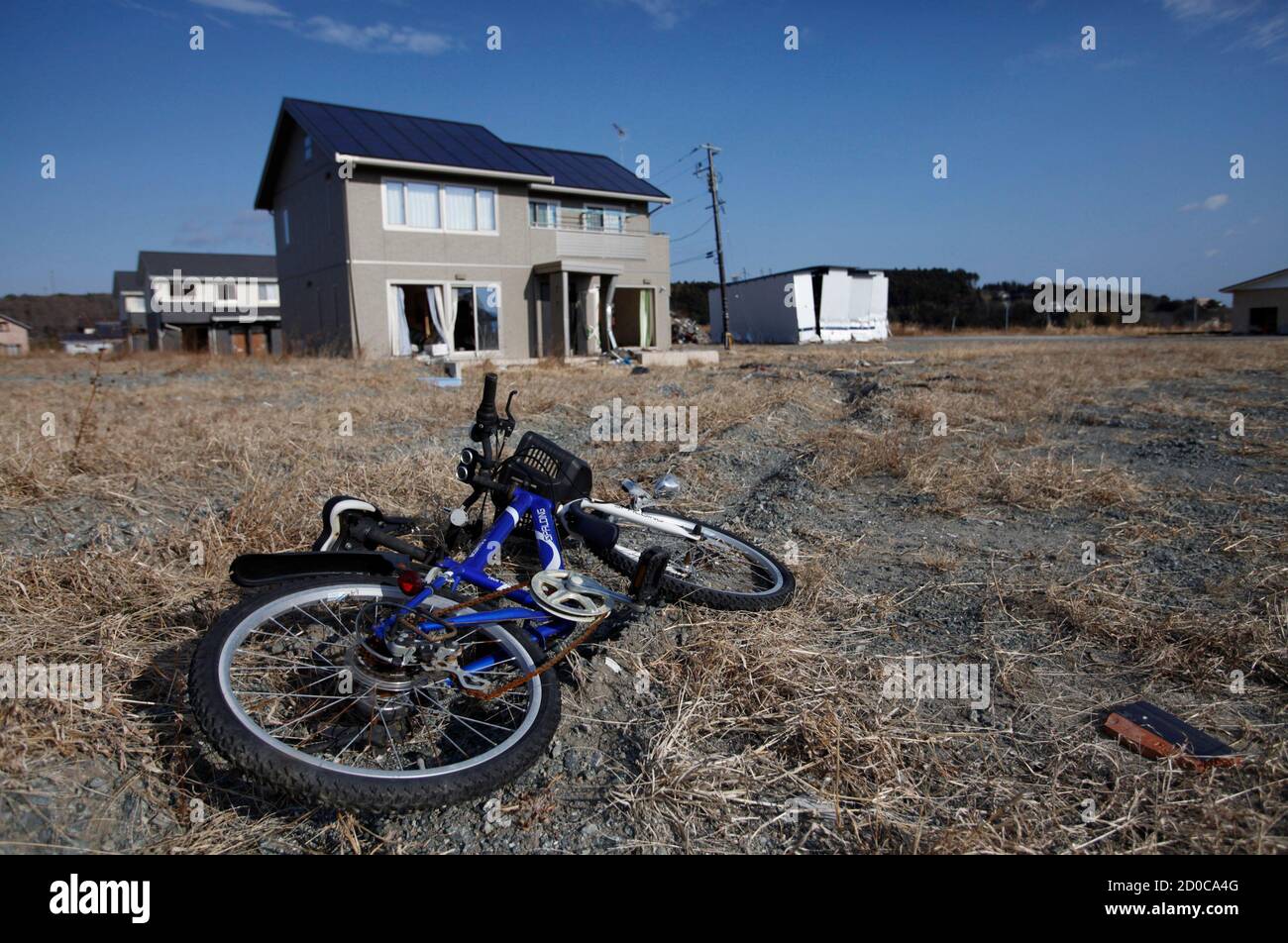 ATTENTION EDITORS - THIS IMAGE IS 2 OF 22 TO ACCOMPANY A PICTURE PACKAGE ON THE EVACUATED TOWNS INSIDE THE 20KM EXCLUSION ZONE AROUND THE FUKUSHIMA DAIICHI NUCLEAR POWER PLANT. SEARCH KEYWORD 'FUKUSHIMA' TO SEE ALL IMAGES PXP900-921.   An abandoned child's bicycle and houses destroyed by the tsunami are seen in Tomioka town, inside the exclusion zone of a 20km radius around the crippled Fukushima Daiichi nuclear power plant, Fukushima prefecture, January 15, 2012. The Fukushima Daiichi nuclear power plant was hit on March 11, 2011 by a tsunami that exceeded 15 metres in some areas. The tsunami Stock Photo
