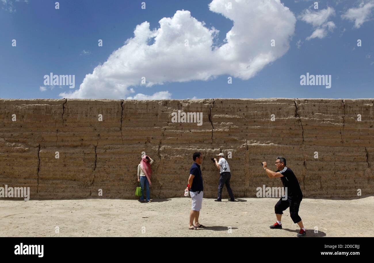 Visitors take pictures next to a section of the Great Wall at Jiayuguan Fort located at the start of the Great Wall of China, near Jiayuguan city, in Gansu province June 17, 2012. REUTERS/Jason Lee (CHINA - Tags: TRAVEL) Stock Photo