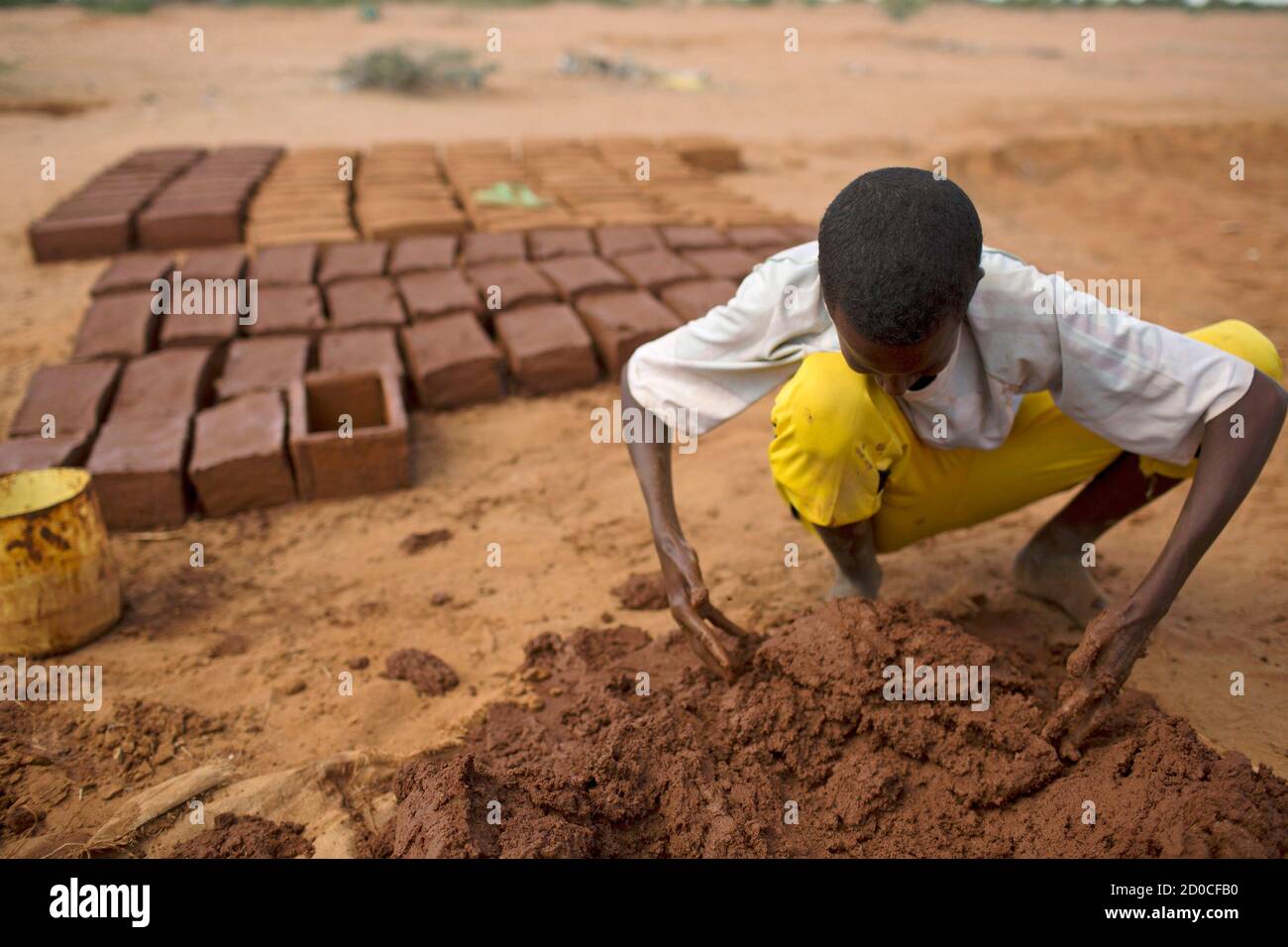 A boy makes construction bricks from mud at one of several refugee settlements in Dadaab, Garissa County, northeastern Kenya October 9, 2013.  REUTERS/Siegfried Modola  (KENYA - Tags: SOCIETY) Stock Photo