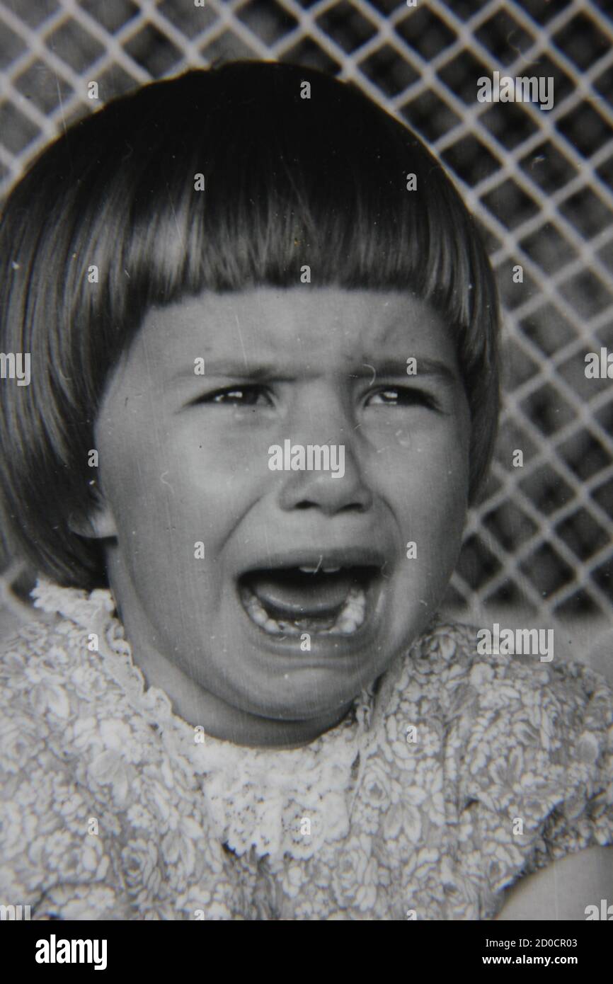 Fine 1970s vintage black and white photography of a little girl hanging out and having a good cry. Stock Photo