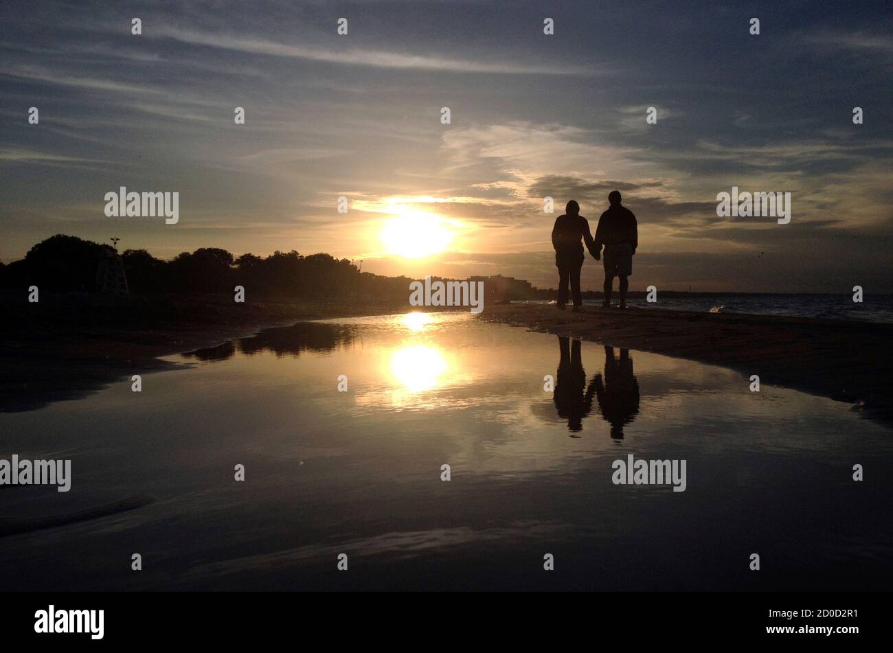 A couple walks along Gillson Beach holding hands as the sun sets in Wilmette, Illinois, June 14, 2014.  REUTERS/Jim Young (UNITED STATES - Tags: ENVIRONMENT SOCIETY) Stock Photo