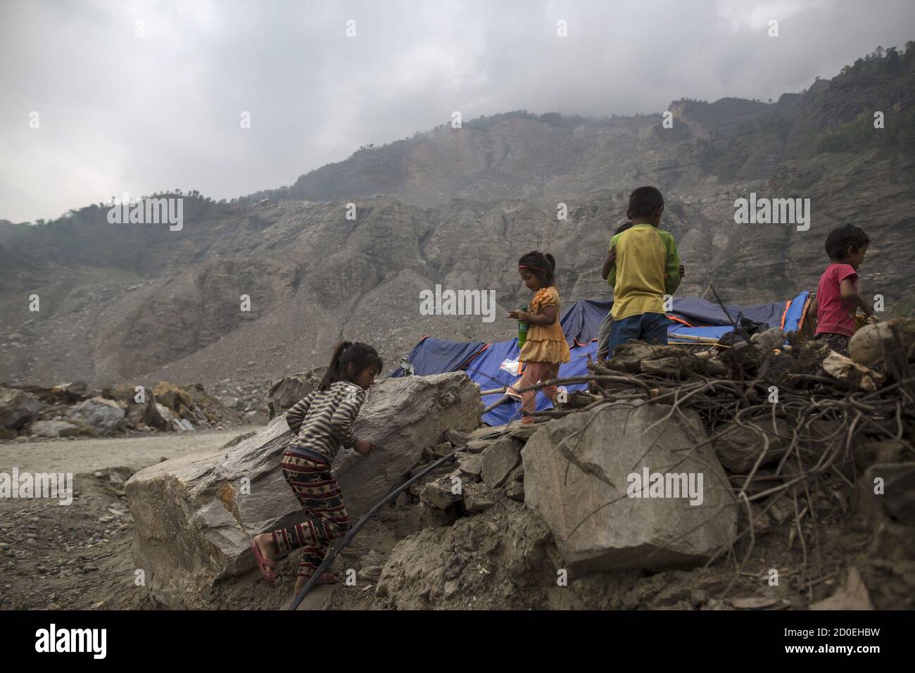 Nepalese children run next to their makeshift shelter near a landslide area after the April 25 earthquake at Jure village in Sindhupalchowk, Nepal, May 9, 2015. Areas of Nepal remain perilously unstable following last month's devastating earthquake, and, as a May 12, 2015 tremor showed, landslides pose an ongoing menace that will only increase when seasonal monsoon rains begin to fall in the coming weeks. Picture taken May 9, 2015. To match QUAKE-NEPAL/MONSOON REUTERS/Athit Perawongmetha Stock Photo