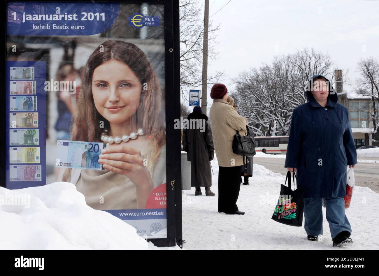 A woman carries shopping bags as she passes a poster informing people about the adoption of the Euro in Parnu December 28, 2010. Estonia will join the Euro zone on January 1, 2011. REUTERS/Ints Kalnins (ESTONIA - Tags: BUSINESS) Stock Photo