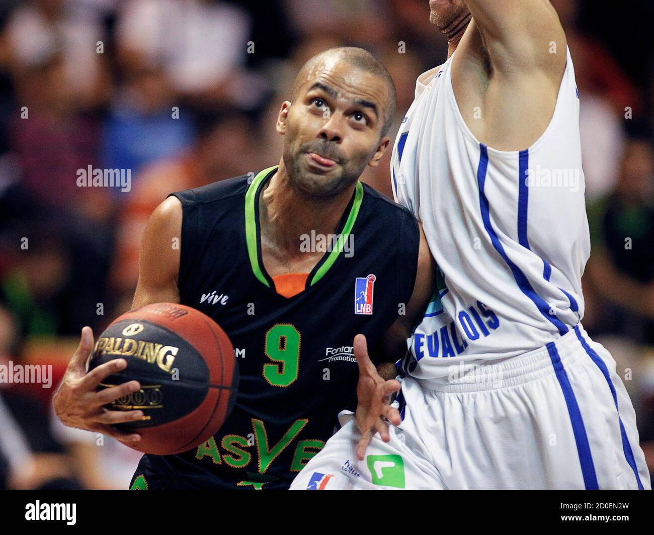 Tony Parker (L), NBA basketball player with the San Antonio Spurs, goes to  the basket past players of Paris Levallois with his French club ASVEL  during their French championship basketball game, in
