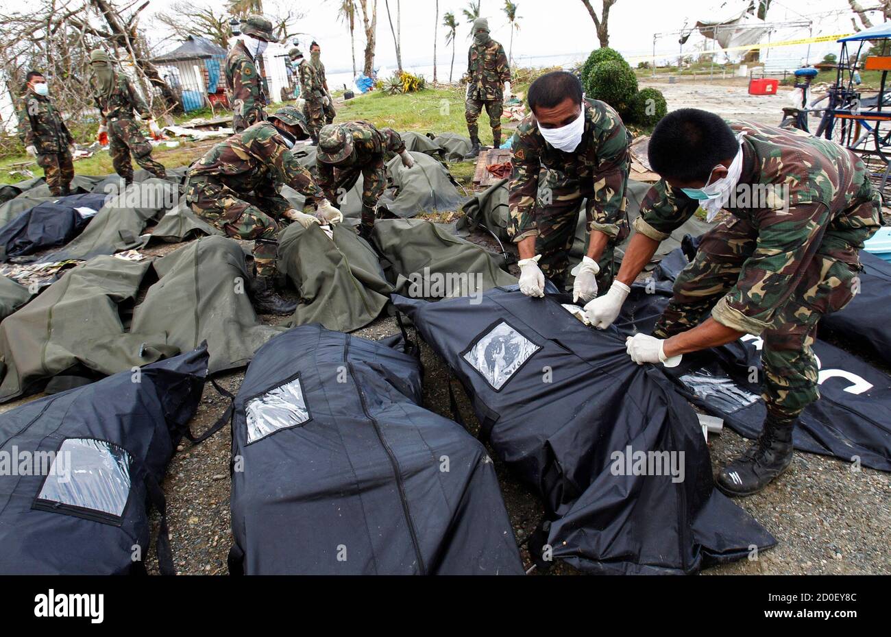 Soldiers zip up body bags after families have identified their relatives who perished during super typhoon Haiyan in Tacloban city, central Philippines November 13, 2013. The government has been overwhelmed by the force of the typhoon, which decimated large swathes of Leyte province where local officials have said they feared 10,000 people died, many drowning in a tsunami-like surge of seawater. REUTERS/Edgar Su (PHILIPPINES - Tags: DISASTER ENVIRONMENT) Stock Photo
