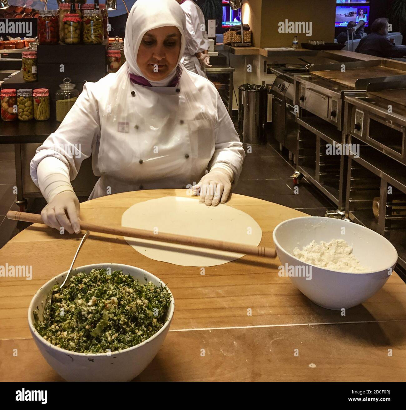 Istanbul, Turkey - 2019-05-04 - airport lounge woman makes snack starting with rolling out dough. Stock Photo
