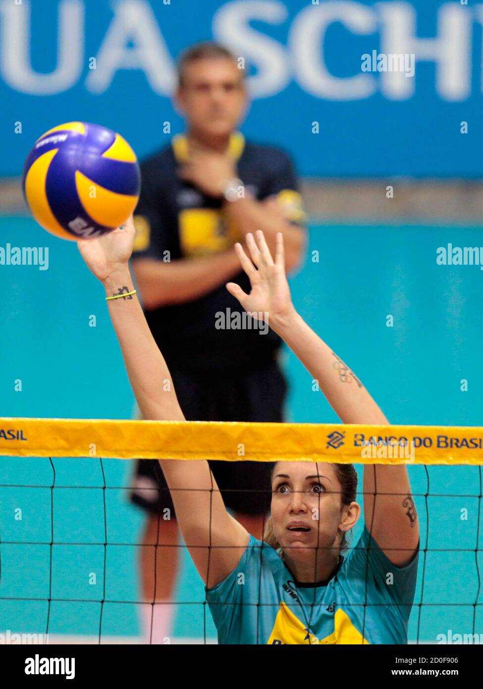 Brazil's volleyball player Thaisa Daher de Menezes blocks a ball near her head coach Jose Roberto Guimaraes during a team volleyball practice at Volleyball Federation's training centre in Saquarema, about 60