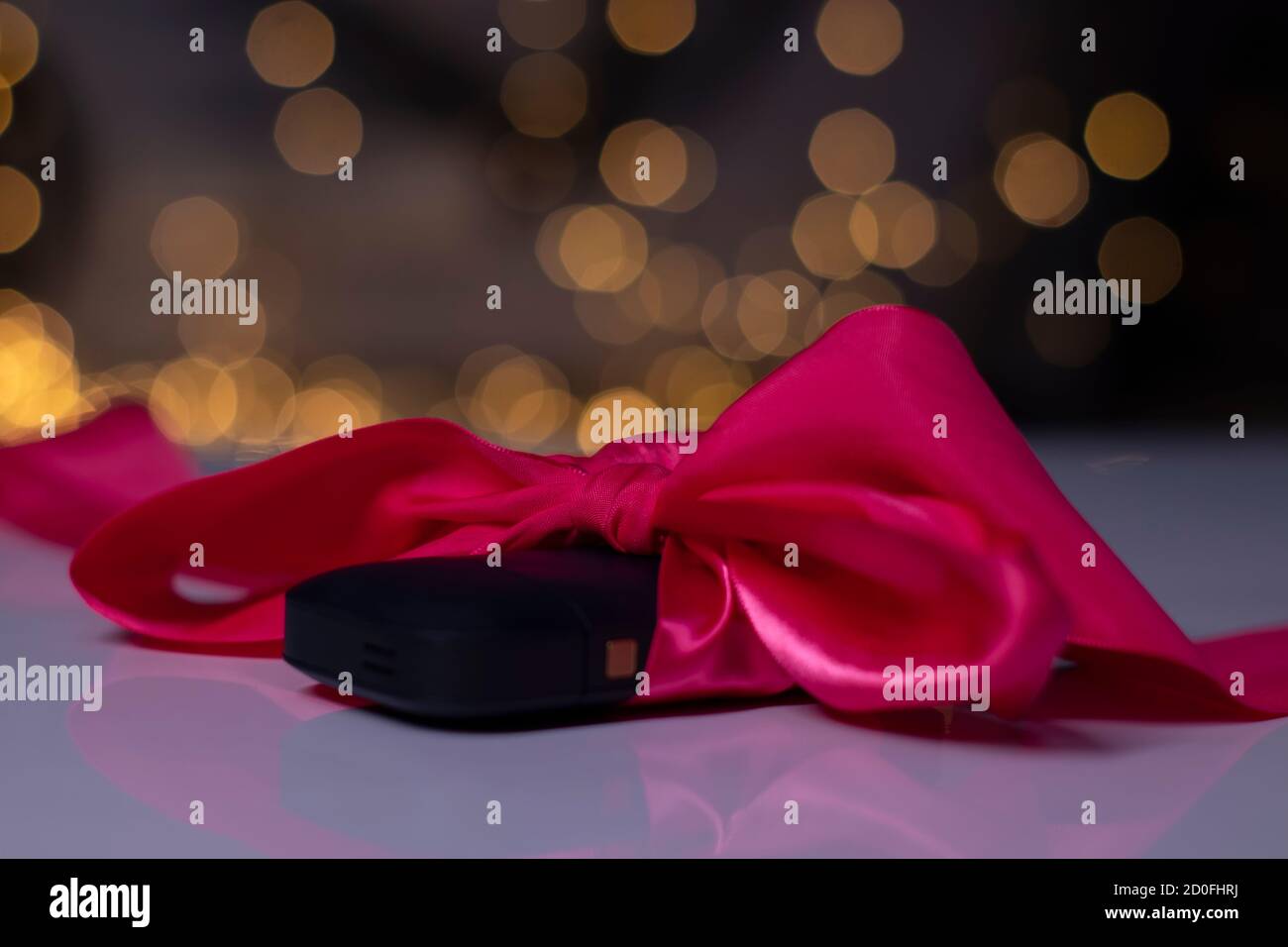 small black gift box with pink ribbon bow on gold bokeh background ...