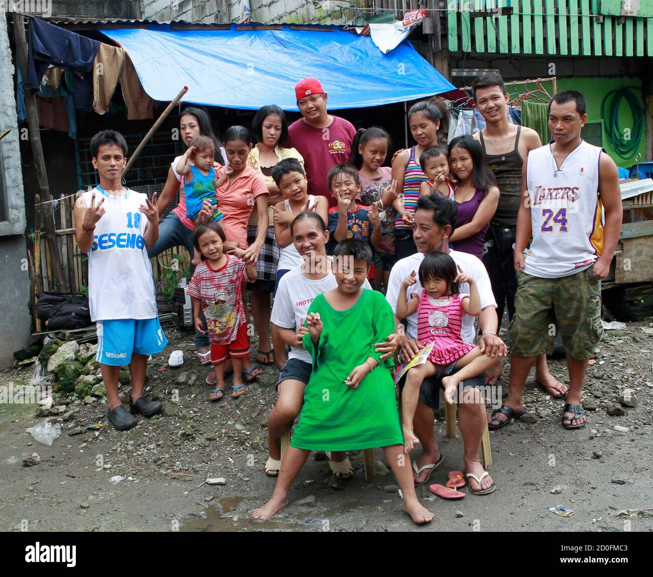 A couple with 22 children, 17 of whom are living, pose for a picture with some of their children and extended family outside their cramped one bedroom apartment in a poor community of Baseco village in Manila August 7, 2011.  The United Nations Population Fund (UNFPA) said that with a population of 94 million, the Philippines is the 12th most populous country in the world and with an average of 2 million babies born every year, the number could hit the 100 million mark by 2015. The United Nations estimates that the world population will reach seven billion this year, making the population almo Stock Photo