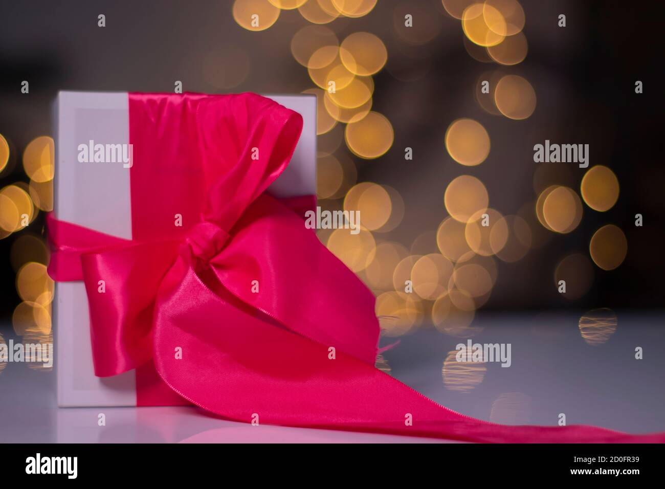 white gift box with pink ribbon bow on gold bokeh background Stock ...