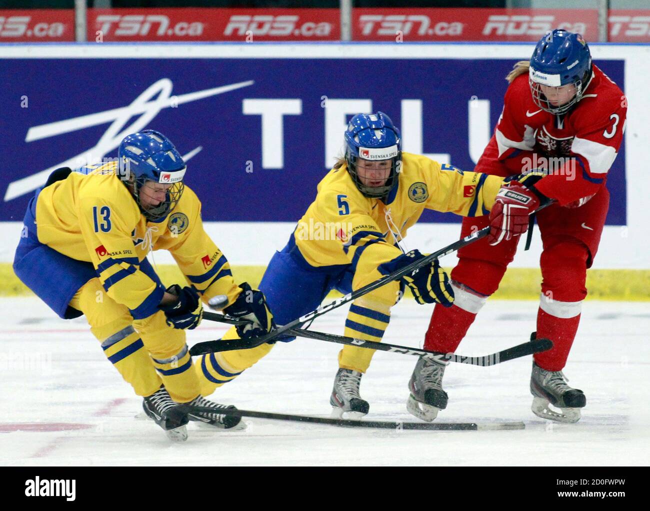 Czech Republic's Klara Chmelova (R) shoots the puck away from Sweden's Lina Wester (L) and Johanna Fallman during the third period of their preliminary round game at the IIHF Ice Hockey Women's World Championship in Ottawa April 2, 2013.     REUTERS/Blair Gable     (CANADA - Tags: SPORT ICE HOCKEY) Stock Photo