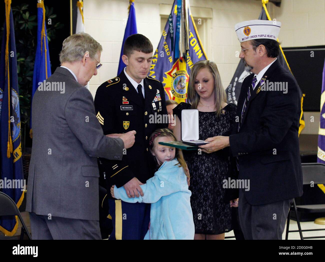 Sen. Mitch McConnell (R-KY) (L) presents Kentucky National Guard Sgt. Jesse Wethington (2nd L) of 623 Field Artillery with the Purple Heart medal as Wethington's wife Ashley and their daughter Hannah, 6, look on at the VFW Post 1170 in Louisville, Kentucky, April 5, 2014.       REUTERS/John Sommers II     (UNITED STATES - Tags: POLITICS MILITARY) Stock Photo