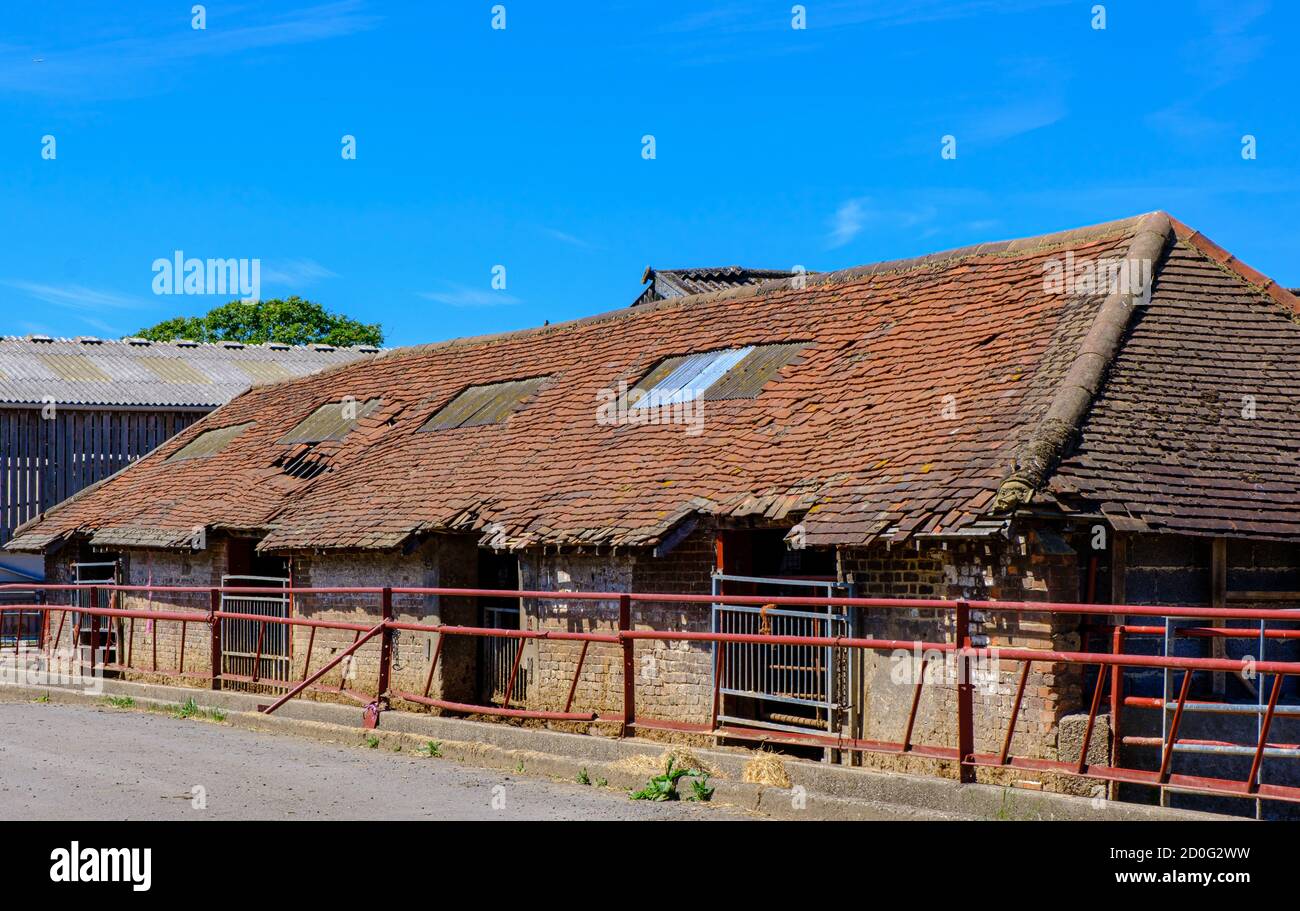 Old dilapidated farm building with broken red tiled roof with 