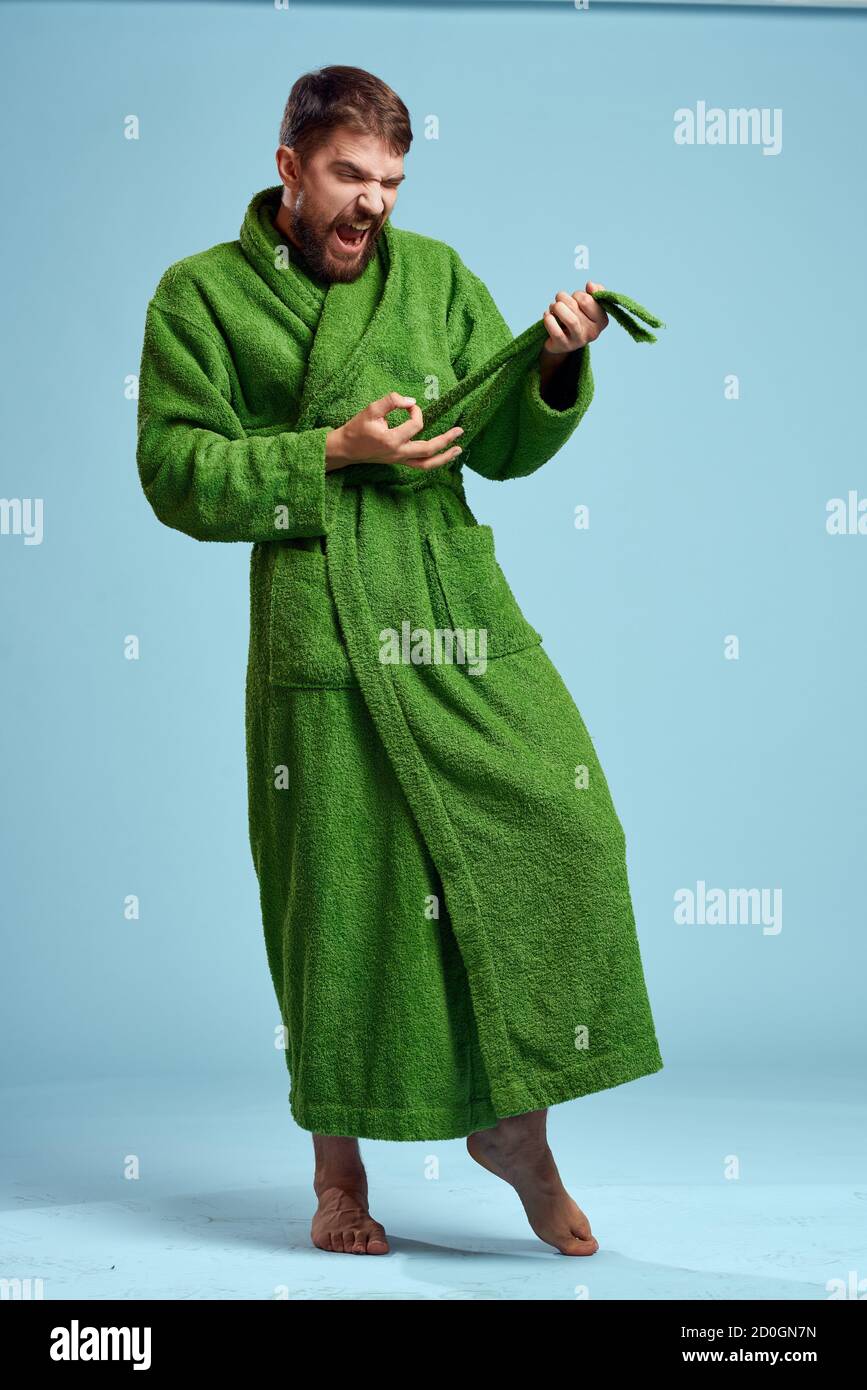 a man in a green robe in full growth on a blue background barefoot