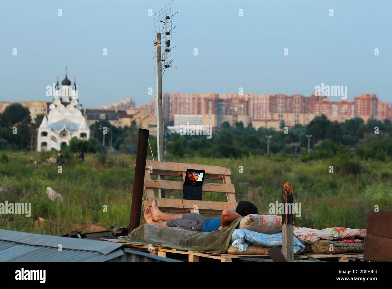 ATTENTION EDITORS - IMAGE 32 OF 34 FOR PICTURE PACKAGE 'MOSCOW'S MIGRANT  WORK FORCE' A migrant worker watches a film on his laptop on top of a  shelter outside Moscow, July 6
