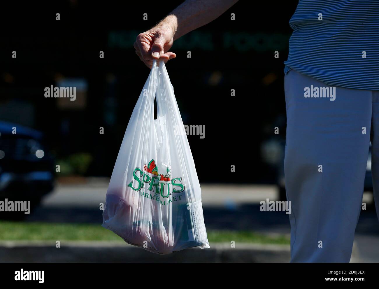 A shopper carries his groceries to his car in a plastic bag after shopping at a Sprouts grocery store in San Diego, California September 30, 2014. Single-use plastic bags are set to disappear from California grocery stores over the next two years under a first-in-the-nation state law signed on Tuesday by Democratic Governor Jerry Brown, despite opposition from bag manufacturers.      REUTERS/Mike Blake (UNITED STATES - Tags: BUSINESS ENVIRONMENT) Stock Photo