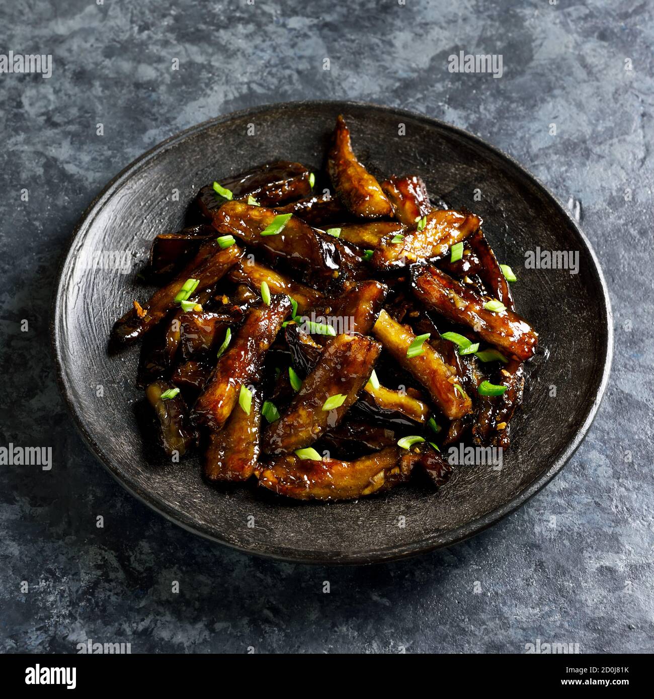 Close up of stirfry Bulgogi Eggplant on plate over dark stone background. Fried aubergine in