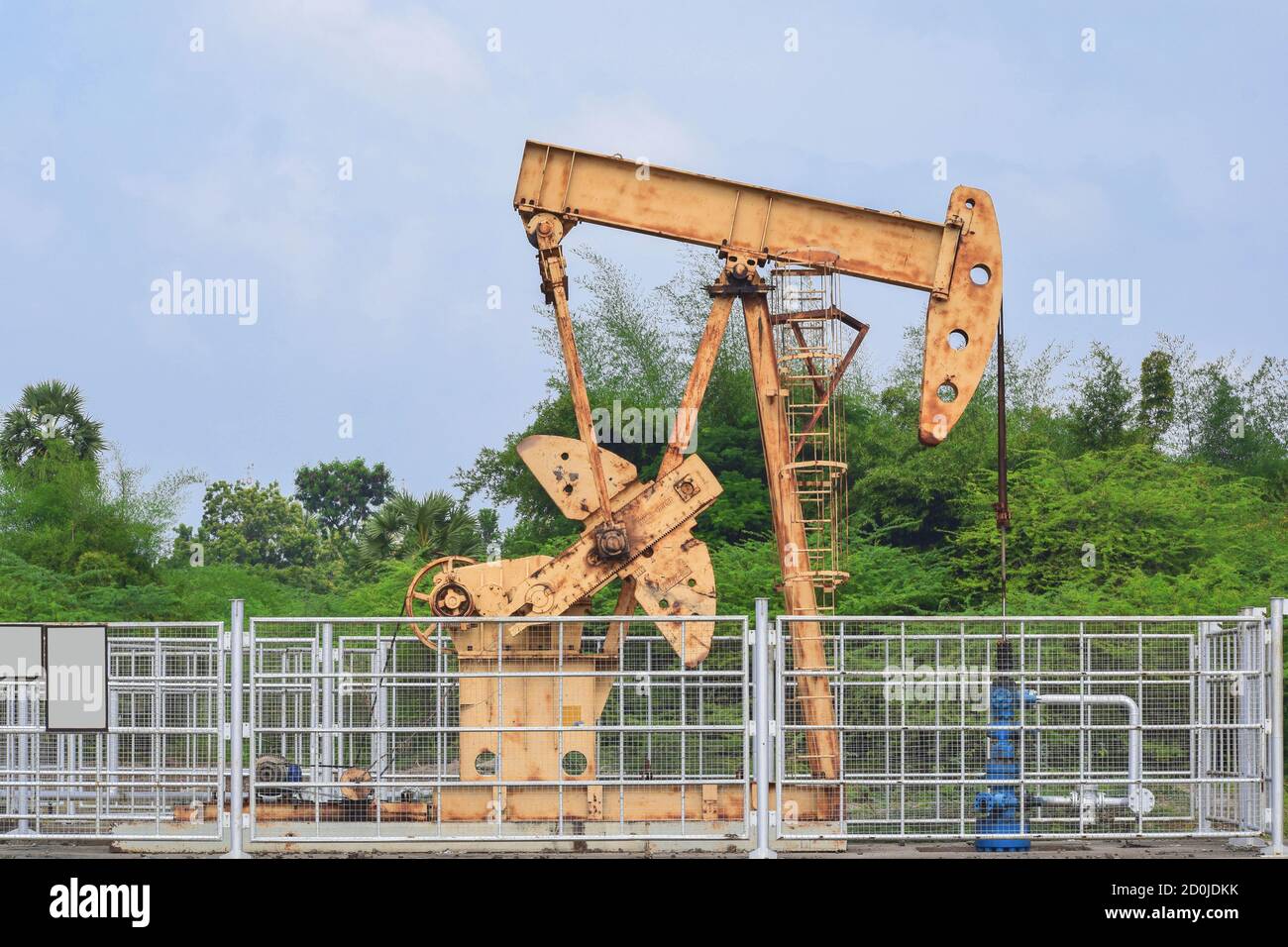Old rusty oil pump jack extracting crude oil and natural gas from well in green background Stock Photo