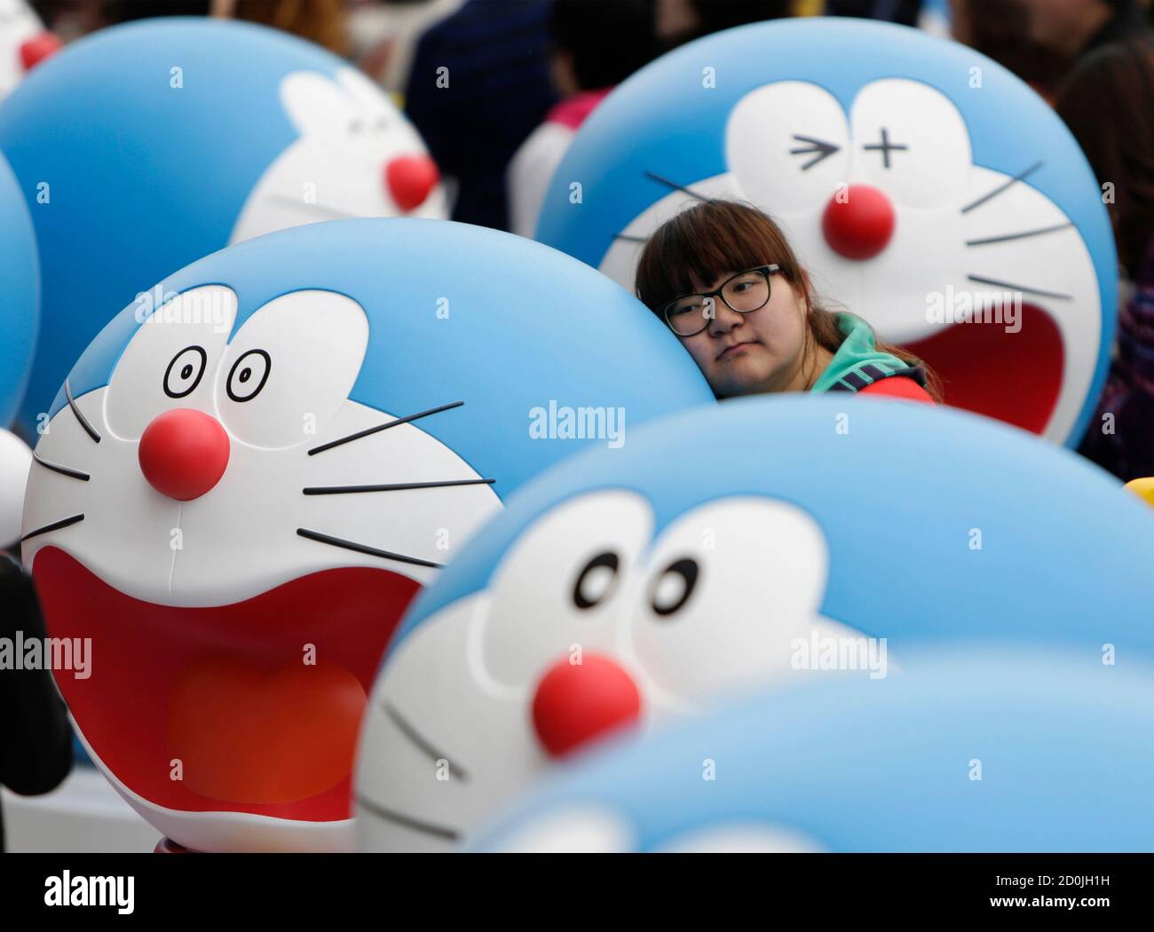 A visitor poses for a photo next to a Doraemon model during an exhibition  in Beijing April 19, 2014. The exhibition, which showcased a hundred models  of the Japanese cartoon character in