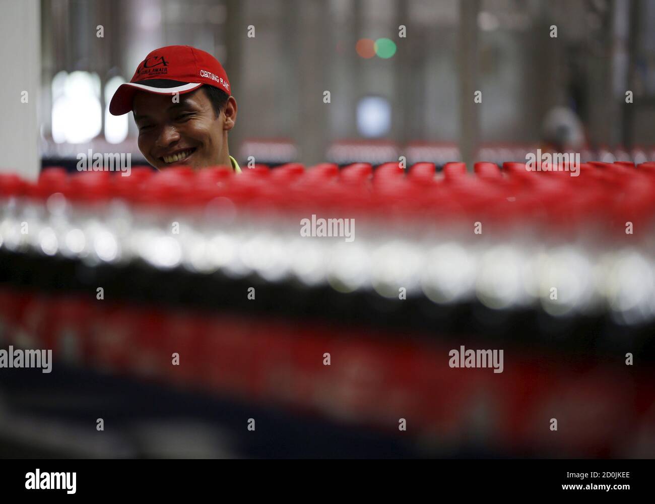 A worker watches bottles of Coca-Cola pass by on a newly inaugurated production line at the Cikedokan Plant in Bekasi, West Java near Jakarta March 31, 2015. The Coca-Cola company inaugurated two new production lines as part of an investment package worth some $500 million to accelerate growth in the Indonesian market.  REUTERS/Darren Whiteside Stock Photo