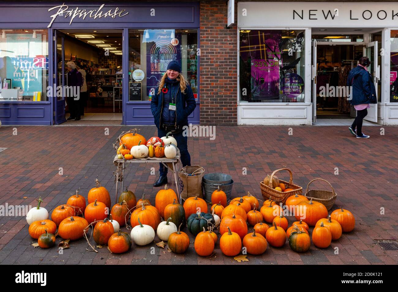 A Young Woman Sells Pumpkins and Squashes, High Street, Lewes, East Sussex, UK. Stock Photo