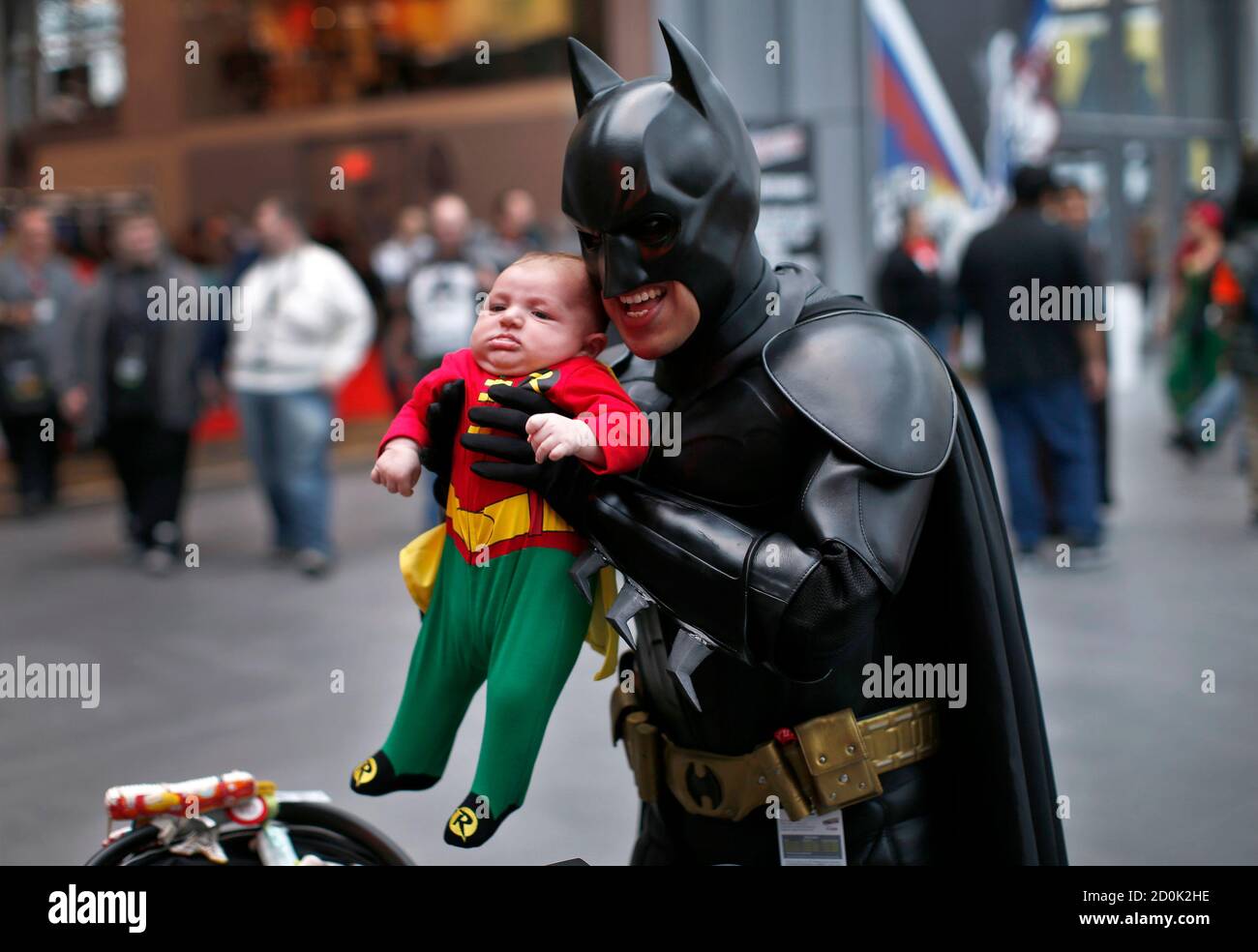 A man in a Batman costume holds up an infant dressed as Robin at New York's  Comic-Con convention October 11, 2013. The event draws thousands of  costumed fans, panels of pop culture