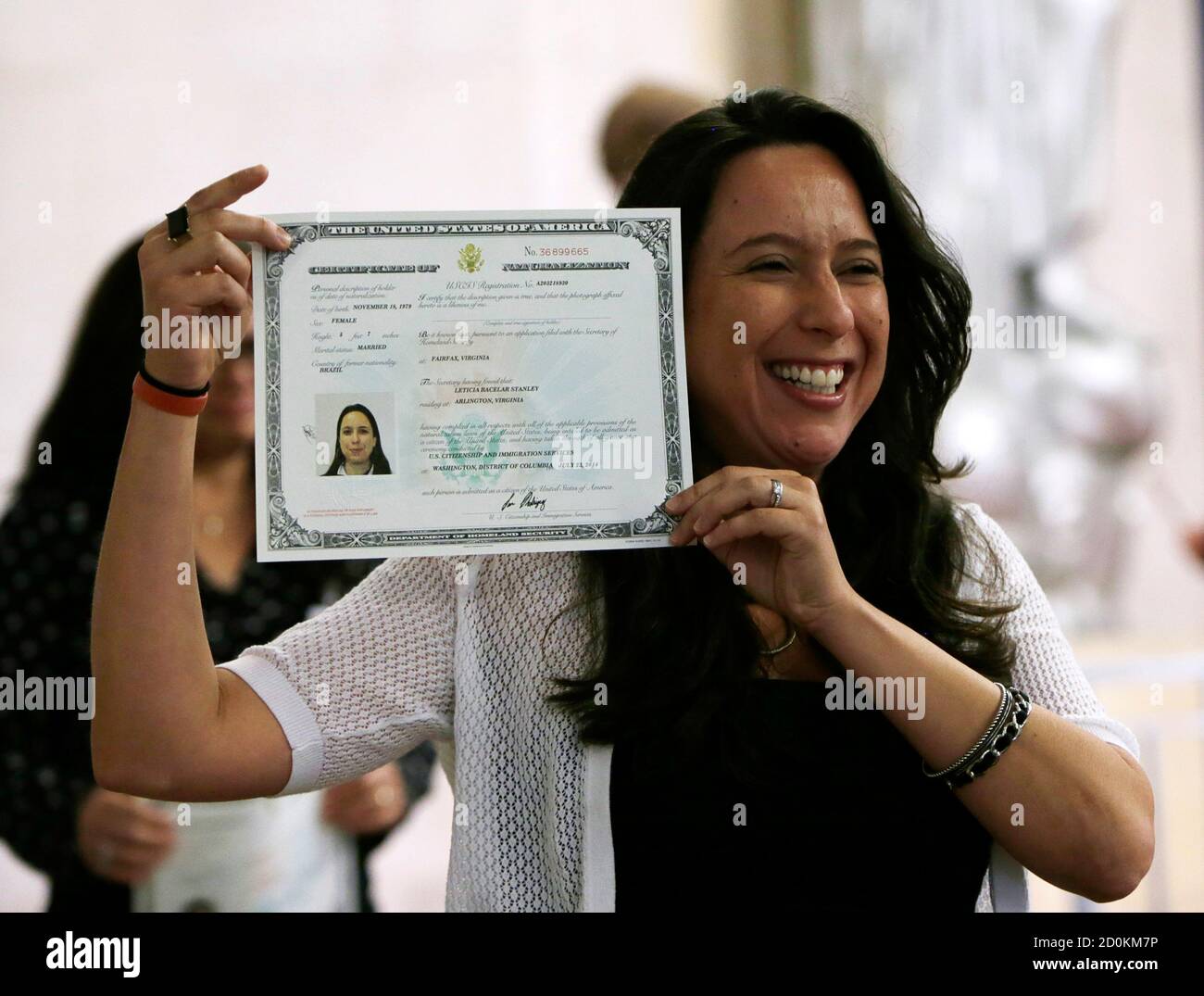 Leticia Stanley proudly displays her certificate of naturalization after  officially becoming a United States citizen during a ceremony for 70  citizenship candidates at the Justice Department in Washington July 22,  2014. Stanley
