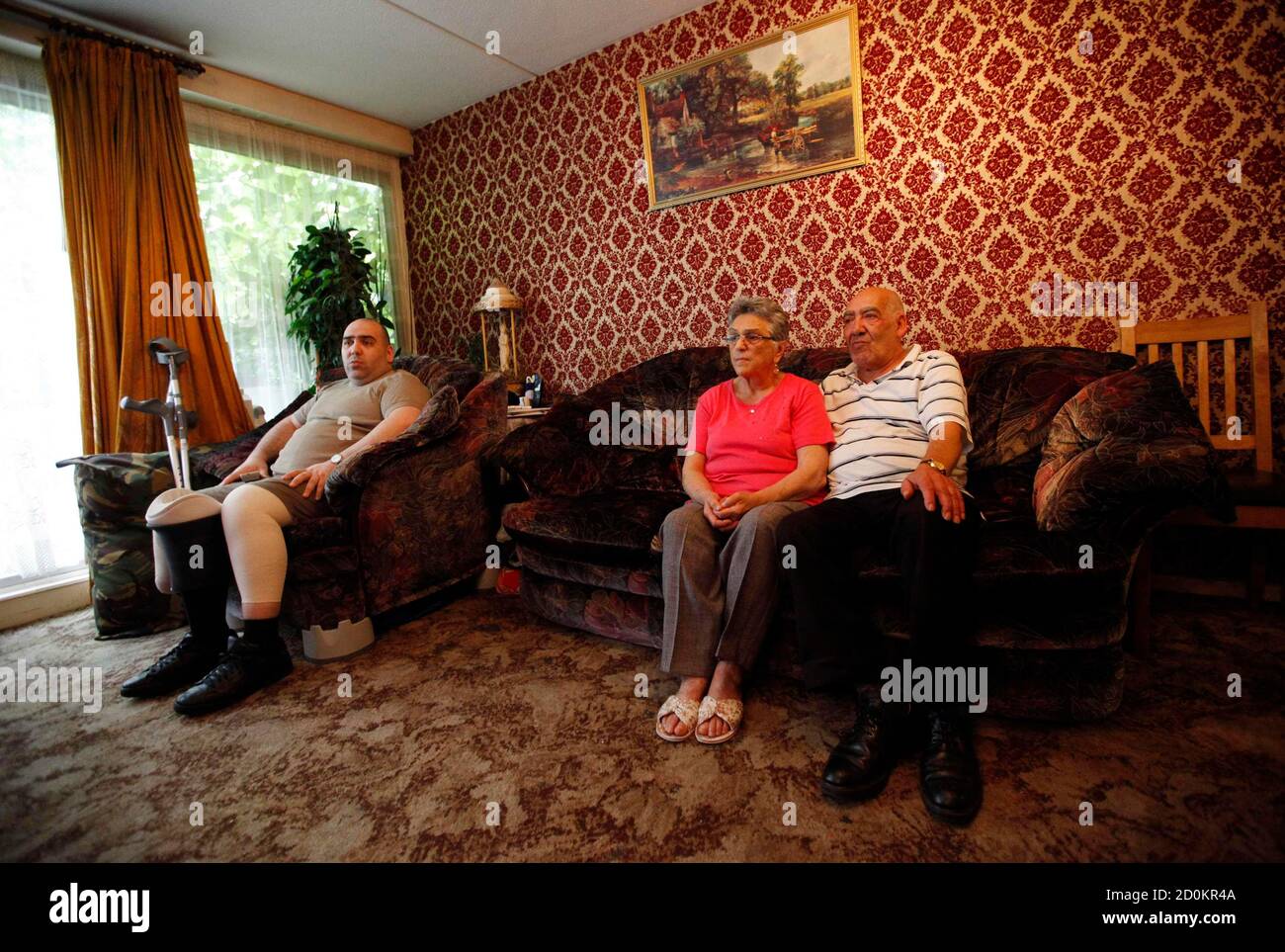 Oner Baduna, (L) his mother Nilgun (C) and his father Ismil watch television in their subsidised apartment near Elephant & Castle in London August 17, 2010. The British government is expected to cut England's social housing budget by 50 percent or more as part of a broad spending review, according to professional body the Chartered Institute of Housing (CIH). The coalition of Conservatives and Liberal Democrats will announce details of its spending review on Wednesday. The aim is to reduce the budget deficit from almost 11 percent of gross domestic product (GDP) to almost nothing in four years Stock Photo