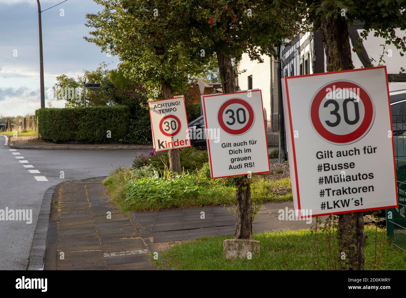 three sign boards on a village road for speed limit 30 kmh, german words pay attention for childrern, this is also for busses, trucks, catarpillars an Stock Photo