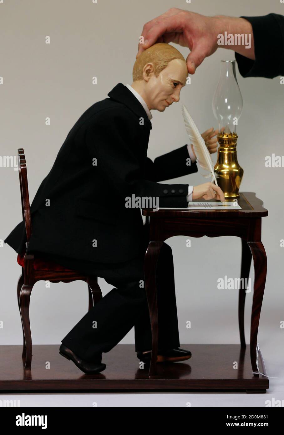 An employee of Technical Antiques Team Breker adjusts the head of a contemporary Musical Automaton depicting Russian President Vladimir Putin, in Cologne October 27, 2014. Inspired by Gustave Vichy's automaton 'Pierrot Ecrivain' of 1895, French artist Christian Baily of Paris portrays Putin signing the 'Treaty of Acceptance of the Republic Crimea into the Russian Federation' from March 18, 2014. The starting price of the automaton in the November 15 auction in Cologne, will be at 18,000 euros (US $ 22,900).  Putin is portrayed with blue glass eyes and molded hair, seated at a rosewood writing  Stock Photo