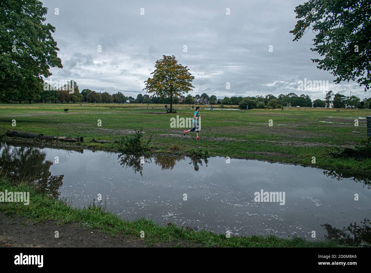 WIMBLEDON LONDON,UK 3 October 2020. A jogger runs past a waterlogged Wimbledon Common following heavy overnight rain brought about by Storm Alex coming from France causing flooding and damage to many parts in Southern England.  Credit: amer ghazzal/Alamy Live News Stock Photo