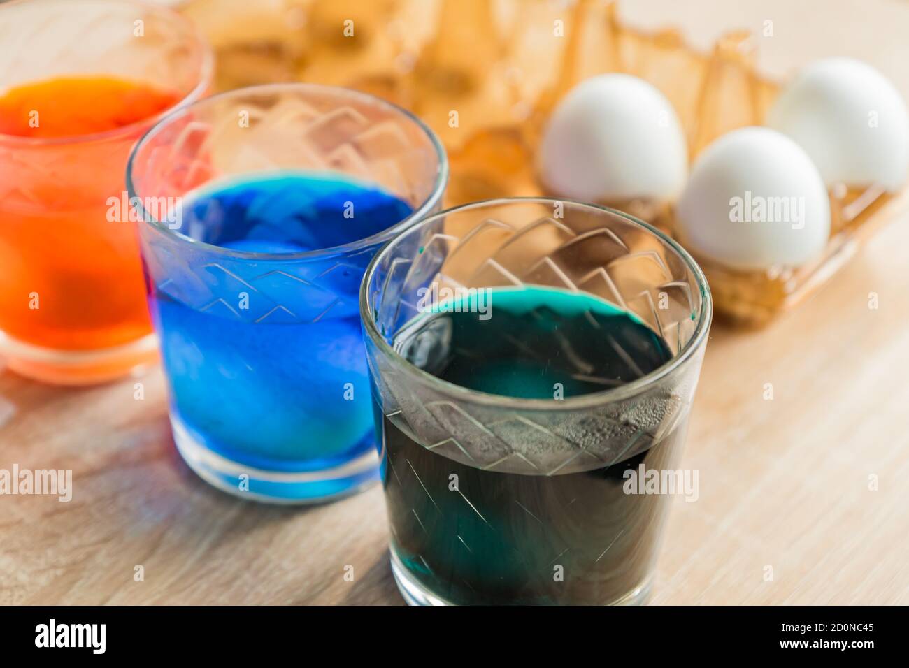 Glass with orange, blue and green paint for Easter eggs. Easter Egg decorating. Stock Photo