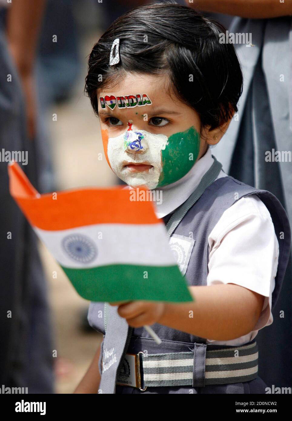 A schoolgirl, with her face painted in colours of the Indian national flag,  holds a flag during Independent Day celebrations inside her school in the  western Indian city of Ahmedabad August 14,